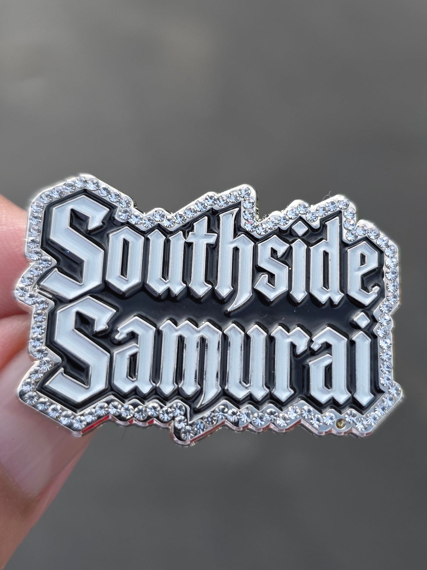 silver enamel lapel pin that reads 'Southside Samurai' in a gothic font, with a border of small clear rhinestones